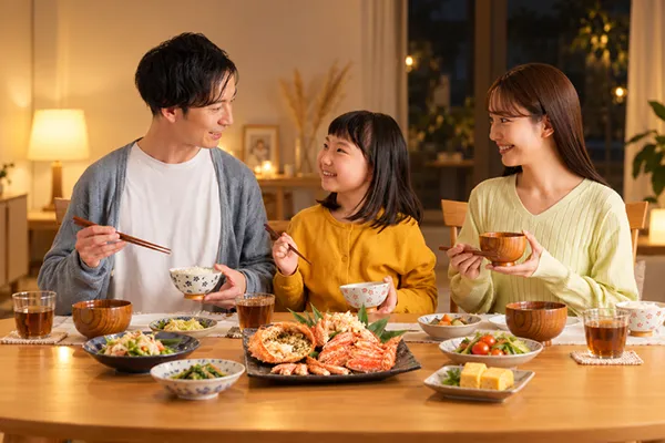 毛ガニの大皿を囲んで乾杯する家族